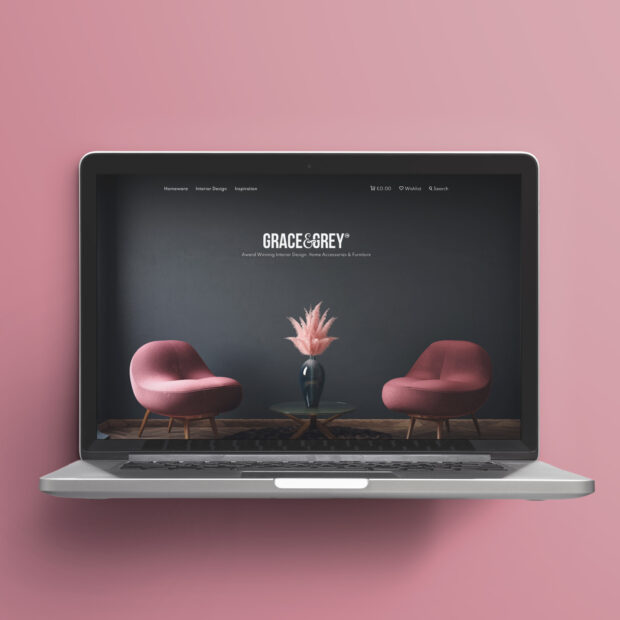 Laptop mockup of the Grace & Grey ecommerce website homepage, showing two pink armchairs either side of a vase with pampas grass, and the tagline 'Award Winning Interior Design, Home Accessories & Furniture.