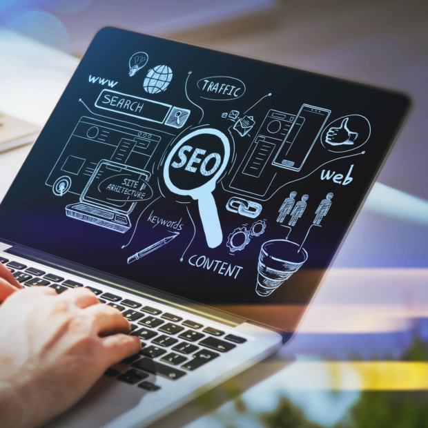 Person typing on a laptop displaying a hand-drawn SEO diagram with icons for search, traffic, keywords, content, and web analytics.
