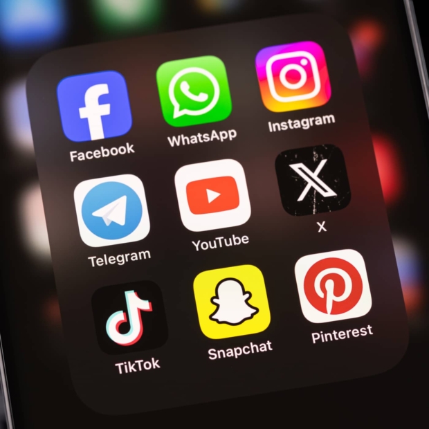 Close-up of a phone screen showing social media app icons including Facebook, WhatsApp, Instagram, Telegram, YouTube, X, TikTok, Snapchat, and Pinterest.