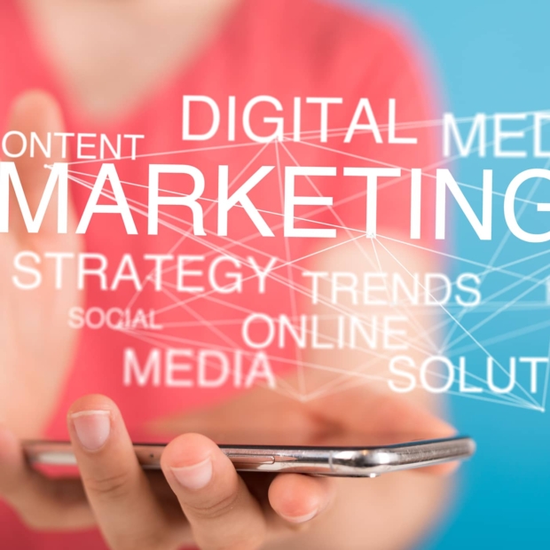 Person holding a smartphone with digital marketing concept words like 'Marketing', 'Strategy', 'Trends', and 'Social' overlaid on a red and blue background