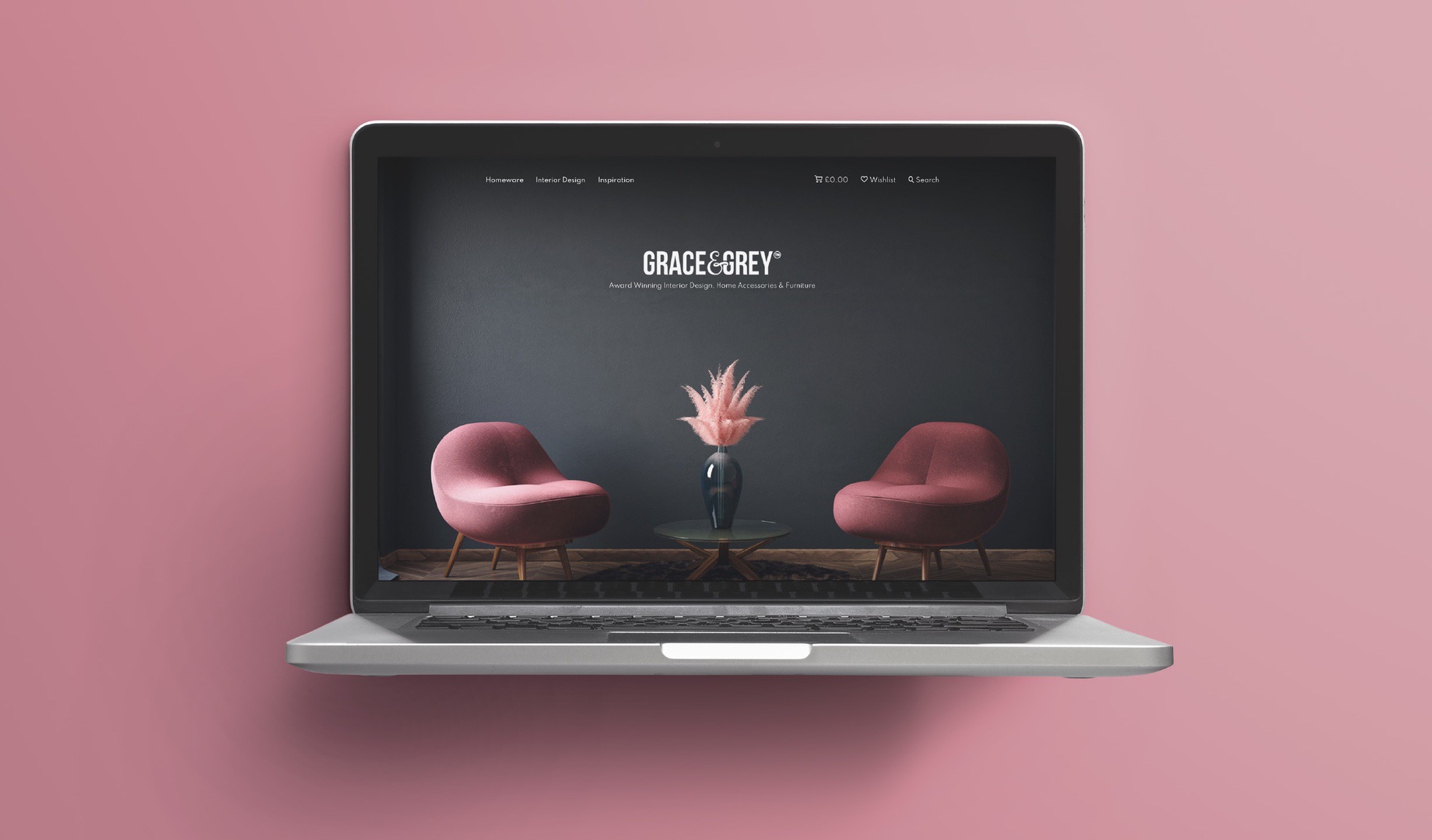 Laptop mockup of the Grace & Grey ecommerce website homepage, showing two pink armchairs either side of a vase with pampas grass, and the tagline 'Award Winning Interior Design, Home Accessories & Furniture.